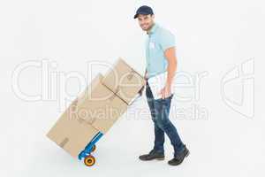 Confident delivery man pushing trolley of boxes