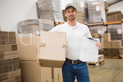 Delivery man with box and clipboard in warehouse