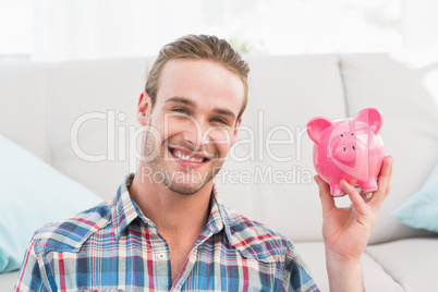 Smiling man showing pink piggy bank Smiling man showing pink piggy bank