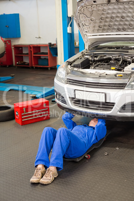 Mechanic lying and looking under car