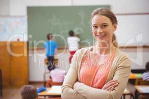 Pretty teacher smiling at camera at back of classroom