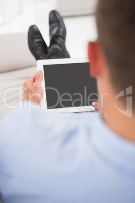 Relaxing businessman on a sofa with a tablet