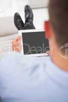 Relaxing businessman on a sofa with a tablet