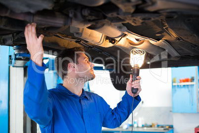 Mechanic using torch to look under car