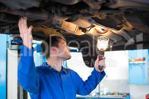 Mechanic using torch to look under car