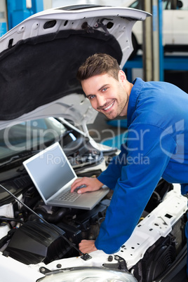 Mechanic using laptop on car