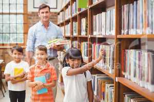 Cute pupils and teacher looking for books in library