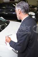 Serious businessman writing on clipboard