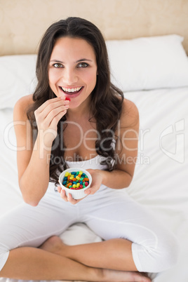 Pretty brunette eating candy in bed