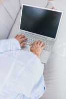 Woman on couch typing on laptop