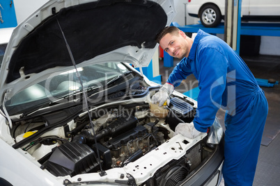 Smiling mechanic working on car