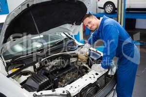 Smiling mechanic working on car