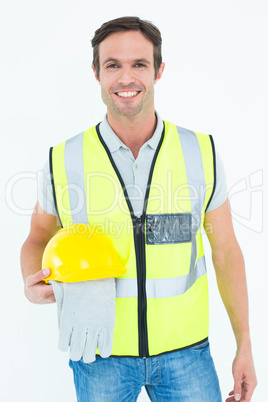 Confident construction worker holding gloves and hardhat