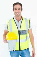 Confident construction worker holding gloves and hardhat