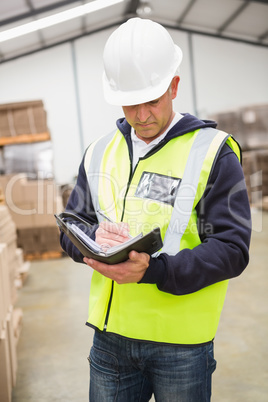 Serious warehouse worker with diary