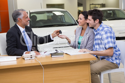 Salesman giving car keys to a couple