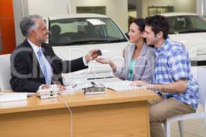 Salesman giving car keys to a couple