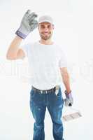 Happy man wearing gloves while holding paint roller