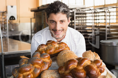 Smiling baker showing board of breads