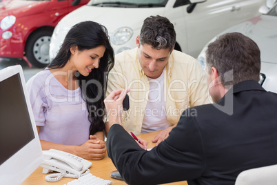 Smiling couple signing salesman contract