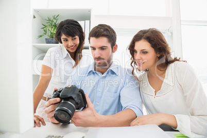 Teamwork holding digital camera and interacting