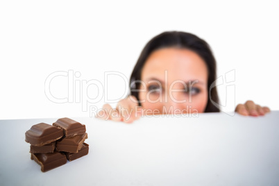 Pretty brunette peeking at chocolate