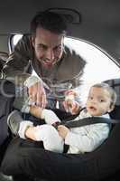Father securing his baby in the car seat