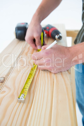 Carpenter with measure tape marking on plank