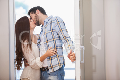 Young couple kiss as they open front door