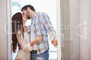 Young couple kiss as they open front door