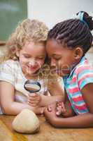 Cute pupils looking through magnifying glass