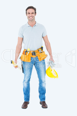 Happy repairman holding spirit level and hardhat