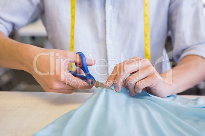 Student cutting fabric with pair of scissors