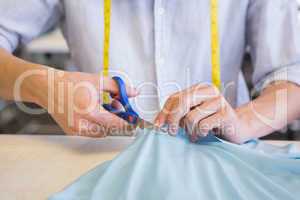 Student cutting fabric with pair of scissors
