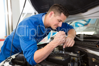 Mechanic examining under hood of car