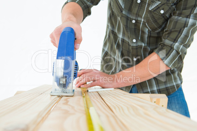 Carpenter cutting wooden plank with electric saw