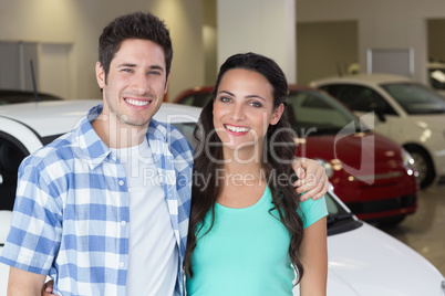 Smiling couple standing in front of a car