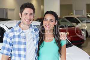 Smiling couple standing in front of a car