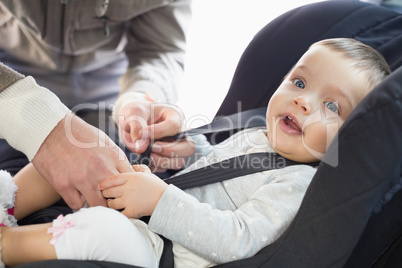 Parents securing baby in the car seat