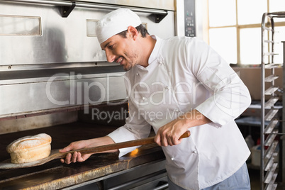 Happy baker taking out fresh loaf