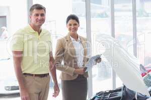 Businesswoman and customer looking at a car engine