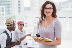 Smiling businesswoman holding phone and notebook