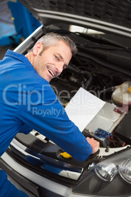 Mechanic examining under hood of car