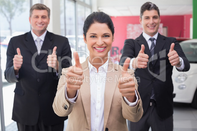 Smiling business team standing while giving thumbs up