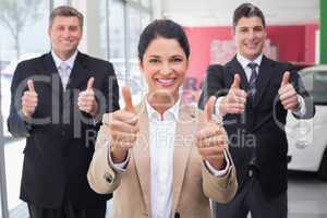 Smiling business team standing while giving thumbs up