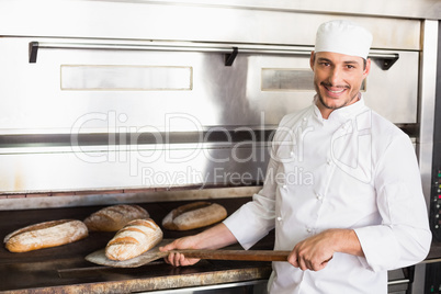 Happy baker taking out fresh loaf