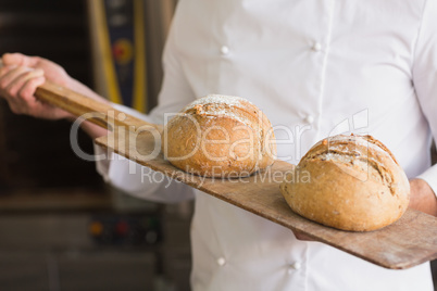 Baker showing tray of fresh bread