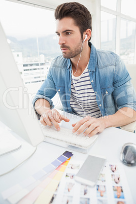 Serious designer enjoying music and typing on keyboard