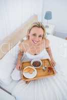 Happy blonde having breakfast in bed