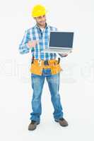Happy construction worker pointing at laptop